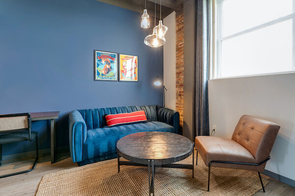 A cozy living room with a blue wall, a blue sofa, a round coffee table, a brown chair, and framed pictures on the wall ends the sentence.