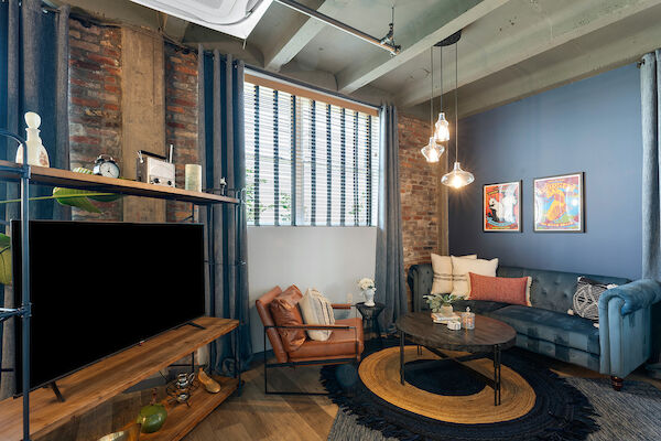 This image shows a cozy living room with a blue and white color scheme, featuring a sofa, armchair, coffee table, TV, and decorative items.