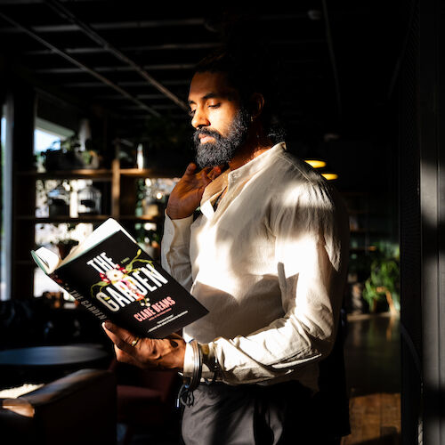 A person is standing indoors, reading a book titled 