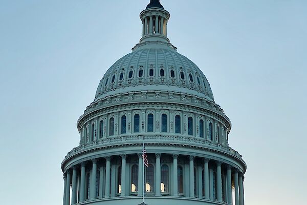 The image shows the United States Capitol building with its iconic dome at dusk.